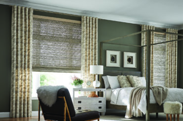 Natural wooden woven shades in a contemporary home bedroom, allowing for some natural lighting. Available at The Blind Broker.