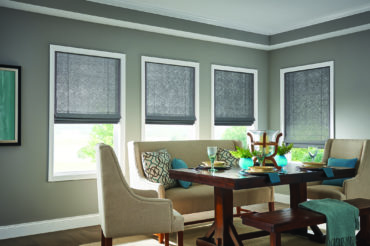 A Kansas City home dining area, sporting 4 large windows, each featuring neutral tone wooden woven shades by The Blind Broker.