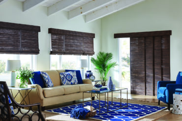 A Kansas City home's interior living space, featuring several picture windows accented by wooden woven shades in natural wooden tones. Available at The Blind Broker.