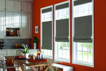 A Kansas City home's kitchen interior, featuring bright red walls and contrasting natural-tone wooden woven shades. Available at The Blind Broker.
