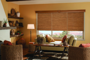 Wooden woven shades in a home's interior living space, lending to the warmth and atmosphere while filtering natural light. Available at The Blind Broker.
