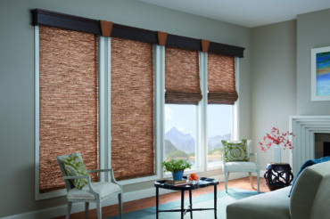 Dark wooden woven shades in a home's interior living space, lending to a filtered light atmosphere. Available at The Blind Broker.