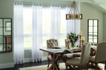 An elegant, brightly-lit dining area with sheer drapes featuring stitched texture patterns. Available at The Blind Broker of Kansas City.
