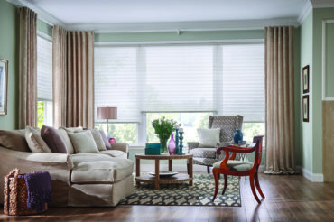 Artian drapes complimenting the pleated shades in this home's living space, offered at The Blind Broker of Kansas City.