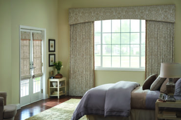 Artisan drapes with classical pattern in a quaint bedroom with neighborhood views. Available at The Blind Broker of Kansas City.