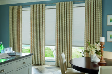Graber Sikar Shades in a home dining area, with accompanying patterned drapes. Available at The Blind Broker of Kansas City.