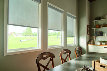 Graber solar shades in a home dining area, filtering natural light for a warm interior living area. Available at The Blind Broker of Kansas City.