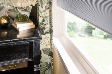 A closeup of Graber's cellular shades, accented by floral drapes. Available at The Blind Broker of Kansas City.