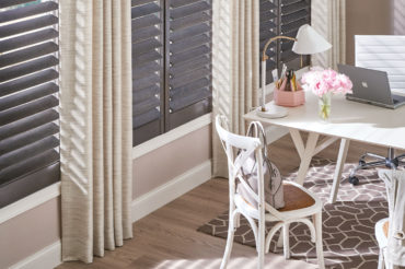 Dark, natural wooden shutters in contrast to a bright home office interior, available at The Blind Broker of Kansas City.