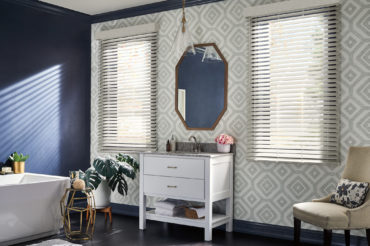 Faux wooden blinds against a geometric accent wall in a home's bathroom. Available at The Blind Broker of Kansas City.