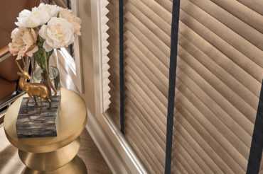 A set of natural wooden blinds over tall living room windows. Available at The Blind Broker of Kansas City.