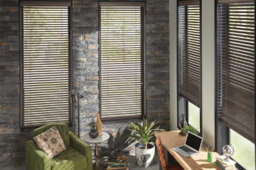 A dark, naturally-finished home office with stone walls and accenting wooden blinds, available at The Blind Broker of Kansas City.