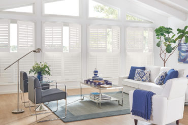 A set of double-hung shutters in a home living space, accenting the custom window shape. Available at The Blind Broker of Kansas City.