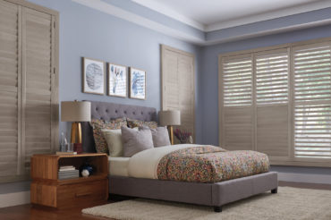Graber wood shutters in a home bedroom, matching the natural finish used in the furniture. Available at The Blind Broker of Kansas City.