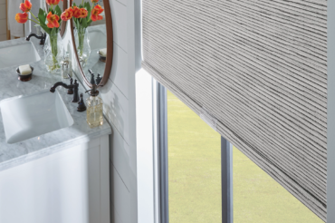 Custom fabric roller shades by The Blind Broker of Kansas City. Featured in a bathroom space, emulating the natural tones within the room.