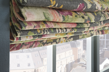 Custom floral fabric shades against the background of a Kansas City neighborhood from within the living space. By The Blind Broker.